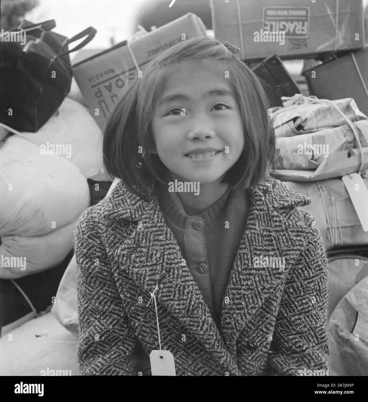 5. August 1942: Hayward, Kalifornien, USA, Ein junges Mitglied einer evakuierten Familie, die auf den Evakuierungsbus wartet. Evakuierte japanischer Abstammung werden für die Dauer in den Zentren der Kriegsumsiedlungsbehörde untergebracht. Kurz nach dem Bombenanschlag auf Pearl Harbor begann Wut und Angst vor japanischen Amerikanern; alle japanischen Abstammung, alt und jung, wohlhabend und Arm, wurden der Spionage verdächtigt. Dieser Verdacht brach schnell auf dem Festland aus; bereits am 19. Februar 1942 ordnete Präsident Franklin D. Roosevelt an, dass deutsche, italienische und japanische Staatsangehörige sowie japanische Amerikaner, die sich in der Lage sahen, sich mit der Vermutung zu befassen. Stockfoto