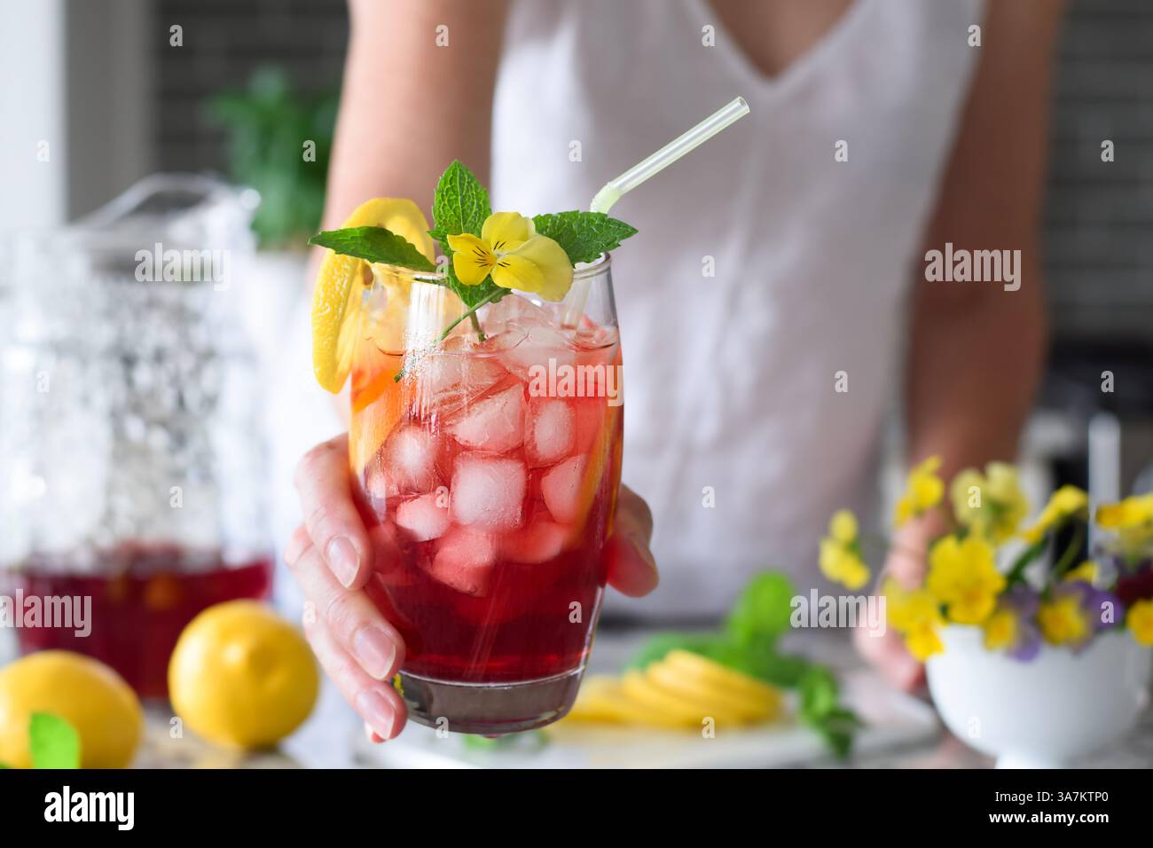 Die Frau greift mit einem farbenfrohen roten, kalten Sommergetränk rein Stockfoto