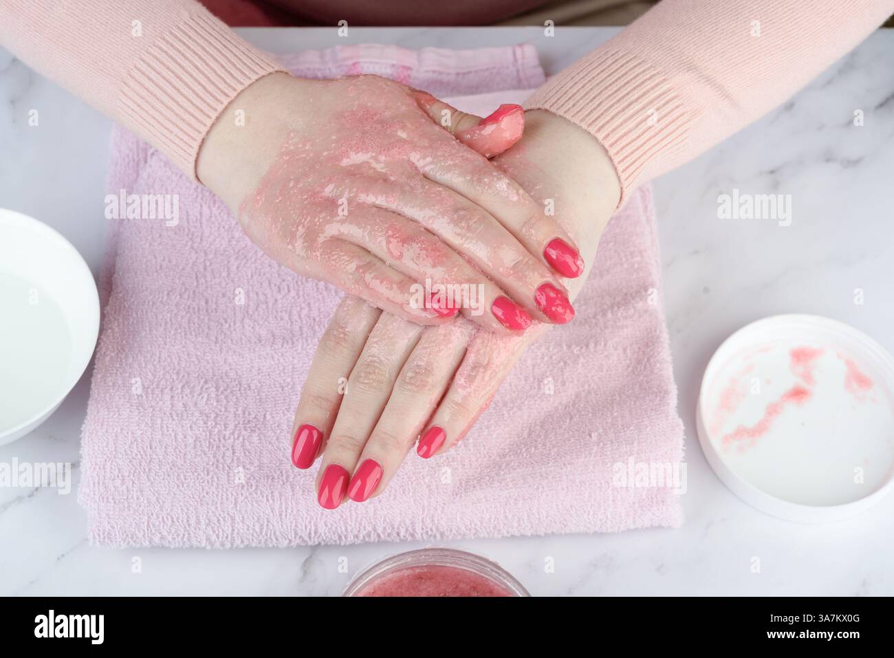 Mit Himbeerpeeling in die Haut der Hände einreiben. Konzept gesunde Hände. Stockfoto