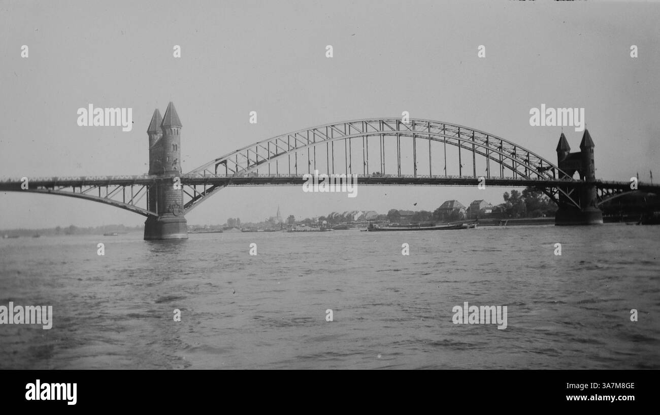 1936, Bonn. Die Alte Rheinbrücke in Bonn, wie sie um 1936 aussah. Diese Brücke verband Bonn mit Beuel über den Rhein. Es hatte einen Stahlrahmen mit markanten Türmen, der den Ingenieurstil des späten 19. Und frühen 20. Jahrhunderts widerspiegelte. Ursprünglich 1898 erbaut, wurde sie in der Zeit des Nationalsozialismus in Klaus Clemens Brücke umbenannt. Die Brücke wurde 1945 während des Zweiten Weltkriegs zerstört und schließlich durch die Kennedy Bridge ersetzt, die auf denselben Piers gebaut und 1949 eröffnet wurde. Aus einer Sammlung nicht zugeschriebener Amateurfotos. Stockfoto