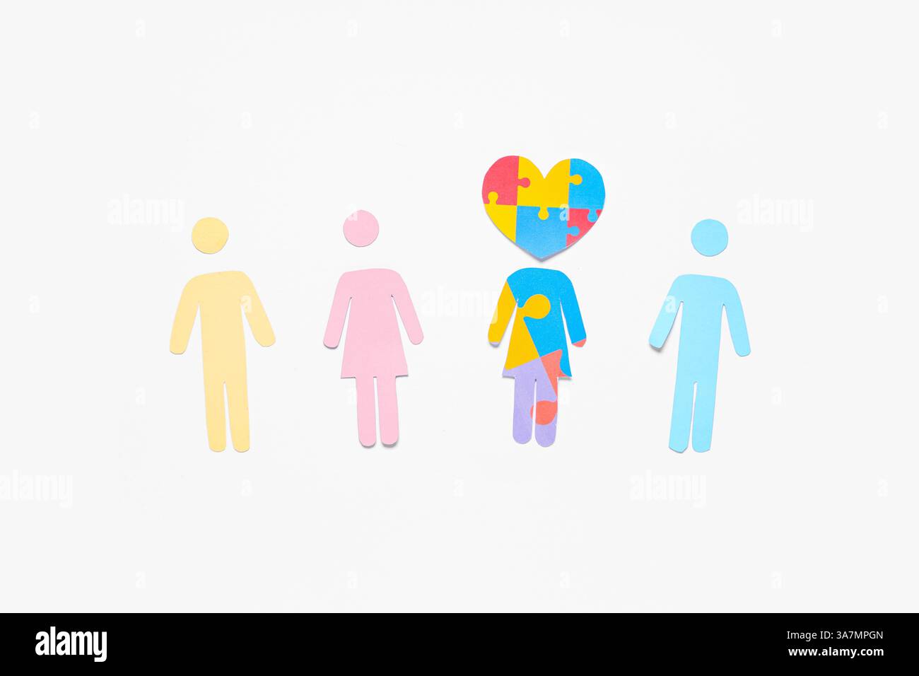 Menschliche Figuren aus Papier mit Herz aus bunten Puzzleteilen auf weißem Hintergrund. Das Konzept der autistischen Störung Stockfoto