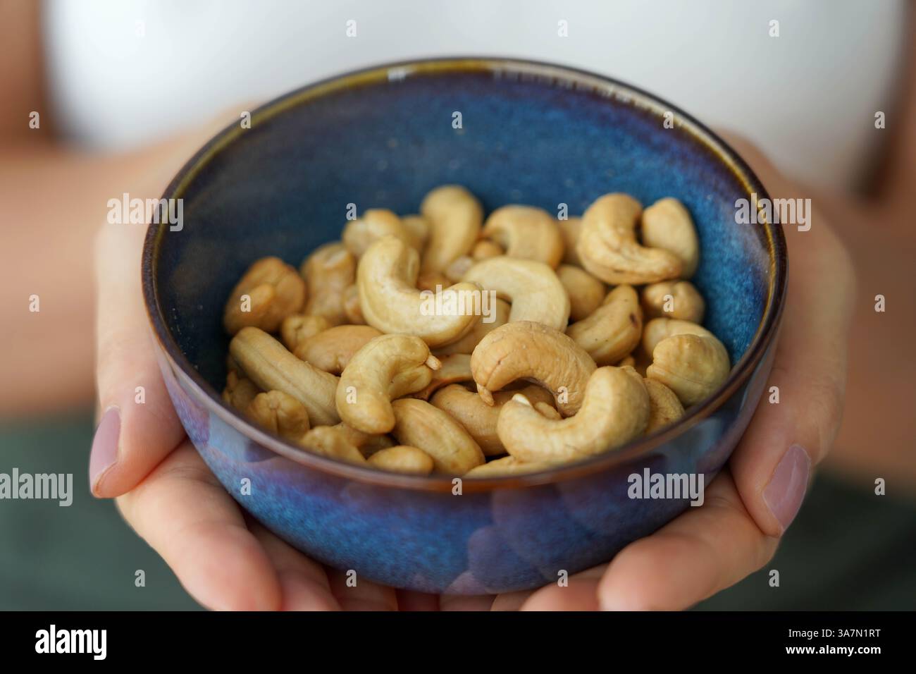 Cashewnüsse. Nahaufnahme von weiblichen Händen, die eine Schüssel voller Cashewnüsse halten. Stockfoto