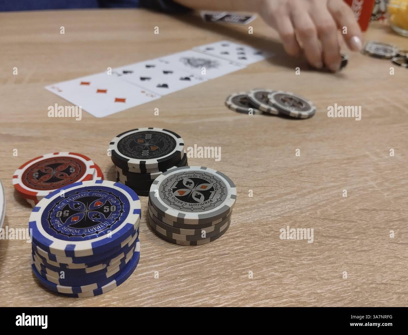 Poker Chips sind blau, rot, grau, silber auf dem Tisch vor dem Hintergrund der Spielkarten. Pokerhände und -Wetten. Poker-Strategie. Stockfoto