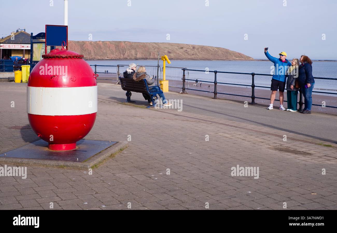 Eine Gruppe von drei Leuten macht ein Selfie in der Nähe der Meeresmine in Filey Stockfoto