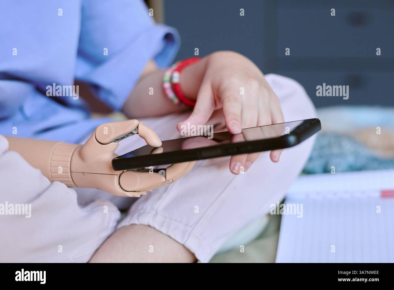 Kind, das ein Tablet mit einer Hand verwendet, bequem auf einer weichen Oberfläche sitzt und entspannt mit der Technologie interagiert Stockfoto