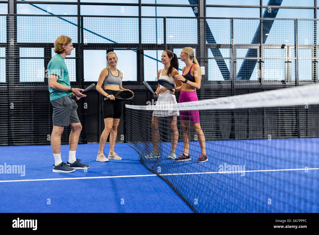 Gruppe von Freunden, die ein Padel-Tennis-Match genießen, lächeln und Schläger halten Stockfoto