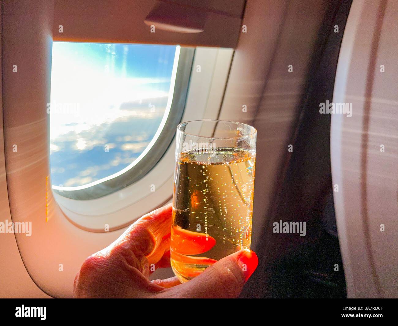 Person mit einem Glas Champagner in der Business-Class-Kabine eines Passagierflugzeugs - Smartphone-aufgenommenes Stockfoto