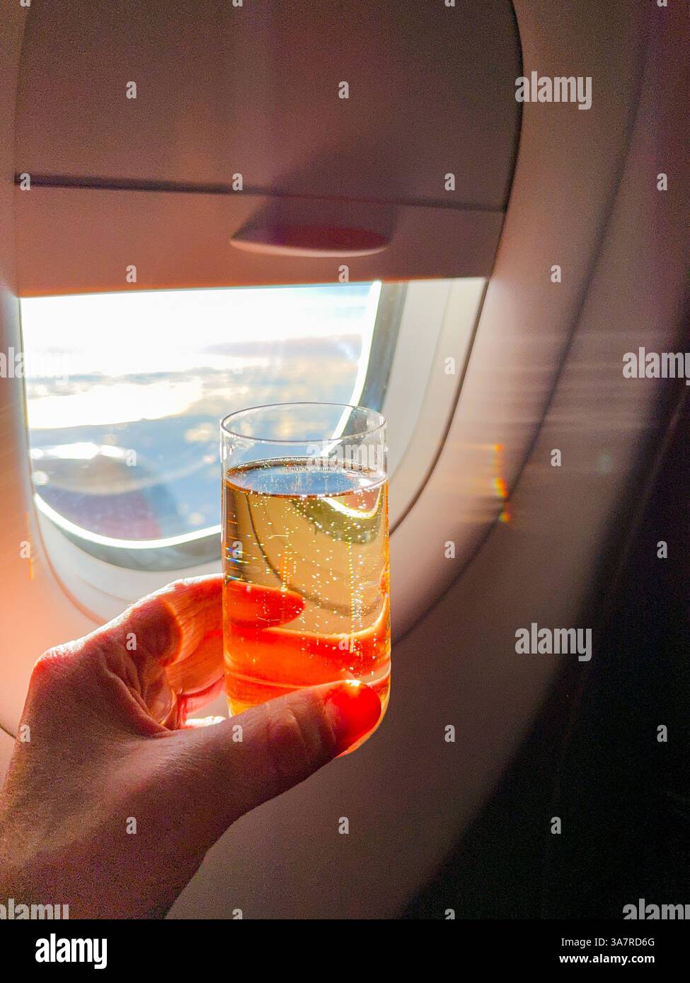 Person mit einem Glas Champagner in der Business-Class-Kabine eines Passagierflugzeugs - Smartphone-aufgenommenes Stockfoto