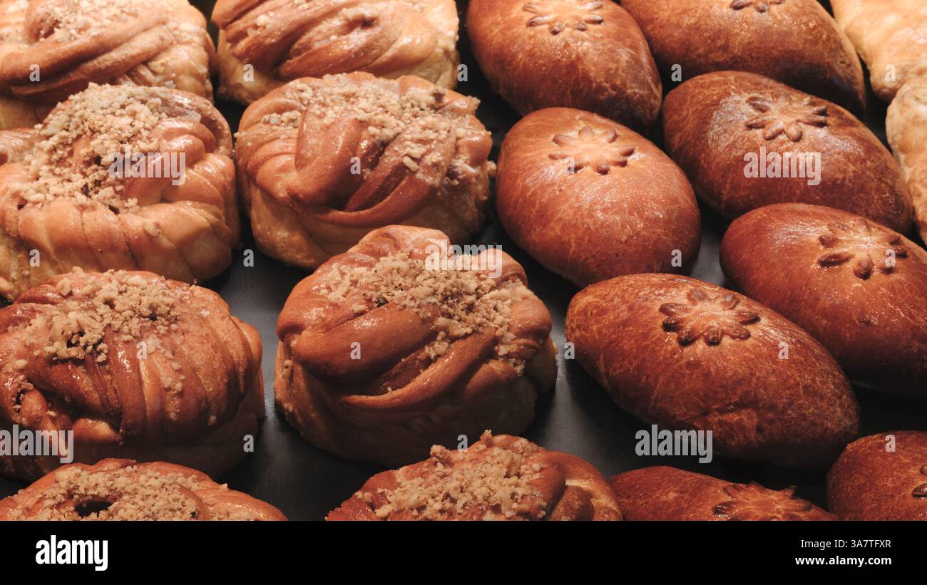 Brot im Regal auf dem Markt oder in der Bäckerei. Auswahl an Gebäck mit verschiedenen Formen und Belägen. Das Gebäck wird nacheinander angeordnet, einige davon sind l Stockfoto