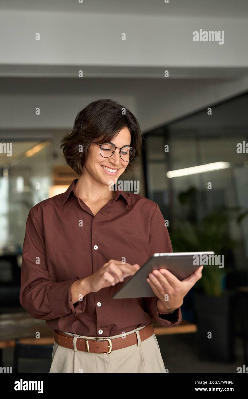 Lächelnde, beschäftigte Geschäftsführerin mit Tablet im Büro. Stockfoto