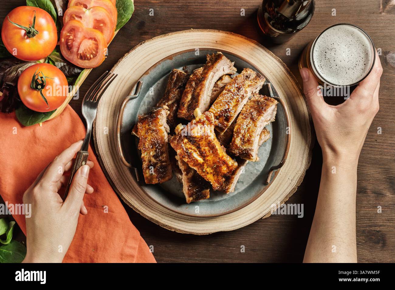 Von oben der Ernte anonyme Person sitzt am Tisch in Cafe mit leckeren Grillfleisch Rippchen und ein Glas Bier Stockfoto