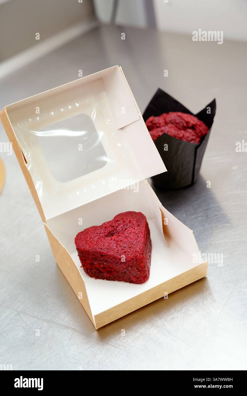 Herzförmiger Kuchen in einer Geschenkbox aus Metall auf einem Metalltisch Stockfoto