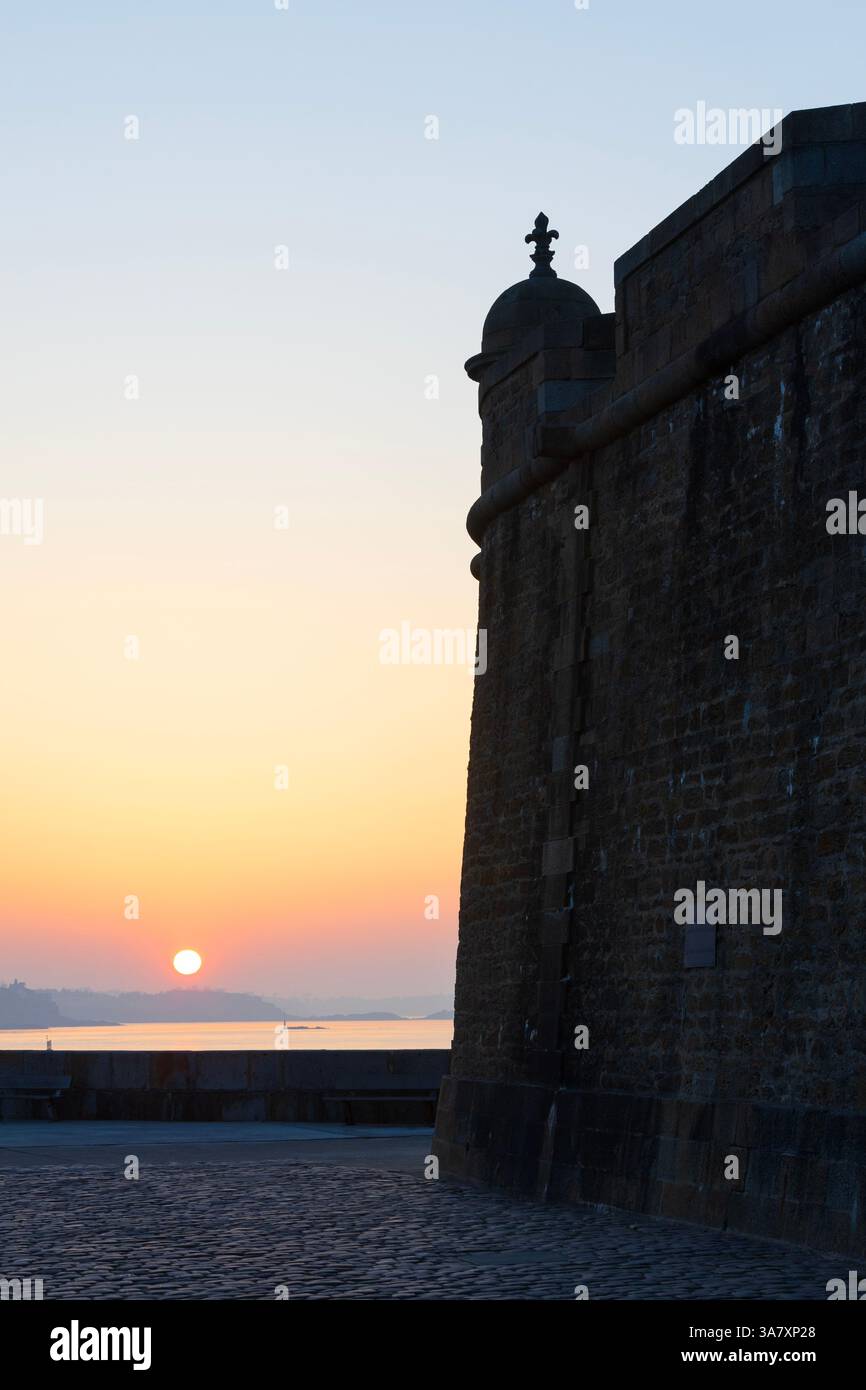 Ein Wachturm mit Fleur-de-Lis-Dekoration auf dem Dach an der mittelalterlichen Stadtmauer von Saint-Malo (Ille-et-Vilaine) in der Bretagne, Frankreich bei Sonnenuntergang Stockfoto