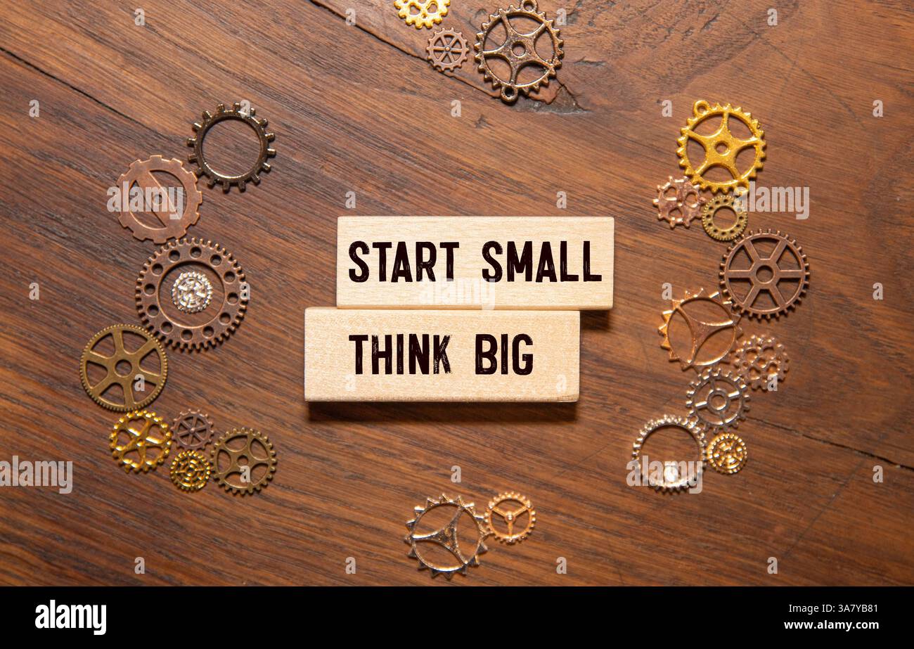 Denken Sie großen Anfang kleines Symbol. Konzeptworte "Think big Start small" auf Holzblöcken auf einem schönen grauen Hintergrund. Geschäftsmann Hand. Business, Motiv Stockfoto