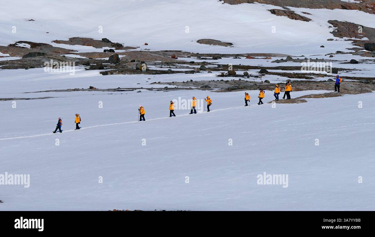 Eine Gruppe von Abenteurern in leuchtend orangefarbenen Jacken wandert auf einer verschneiten Piste im Svalbard-Archipel in Norwegen Stockfoto