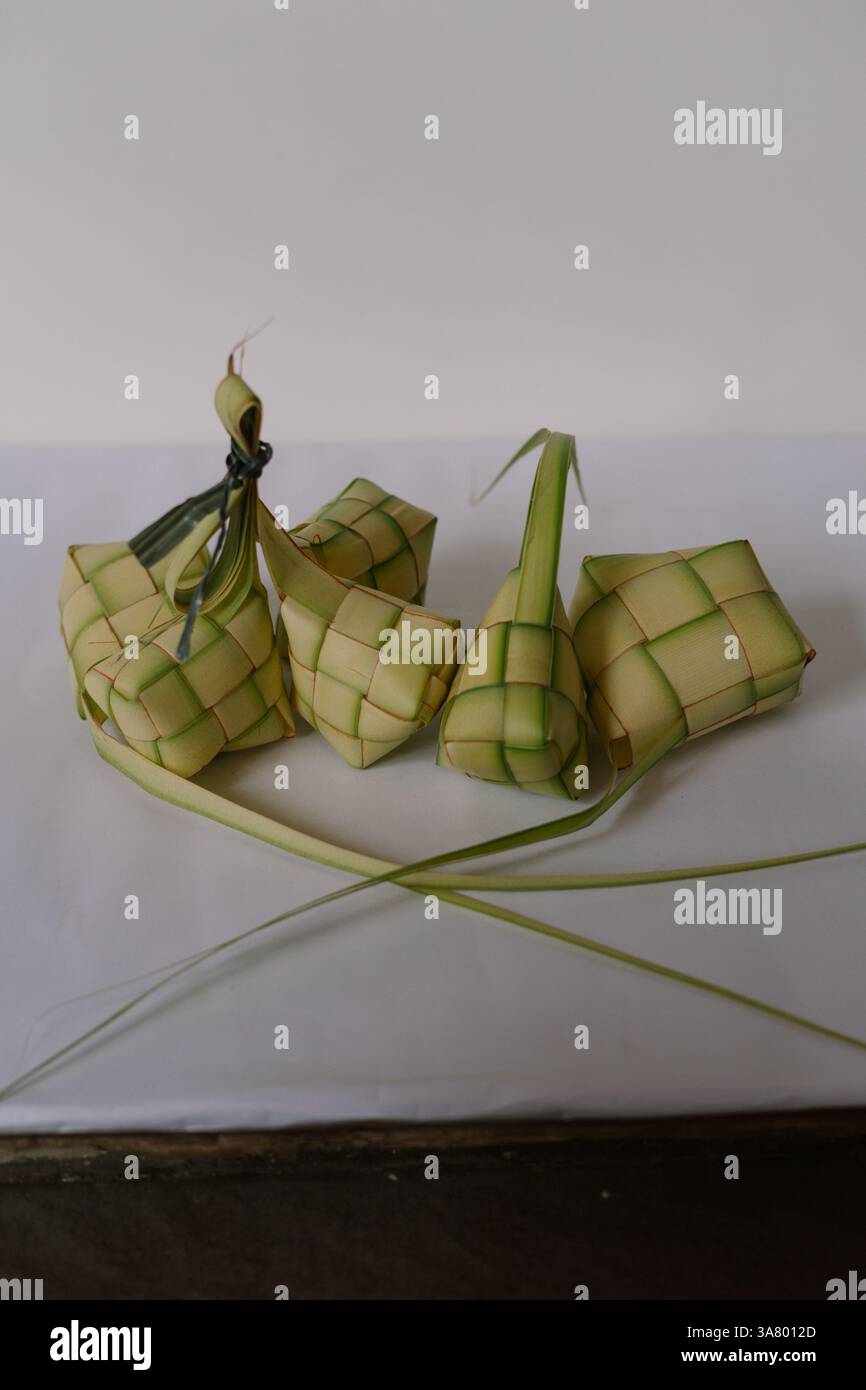 Eine Gruppe von Ketupat, diamantförmigen Reisknödeln, die in gewebten Palmblattbeuteln gekocht werden. Dies ist ein beliebtes Gericht in Südostasien, das oft während der fes serviert wird Stockfoto