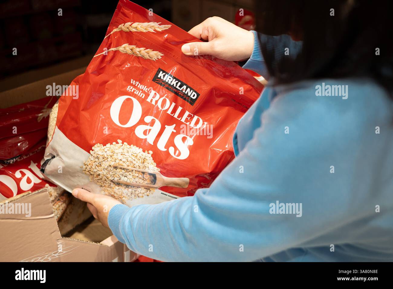 Ein Käufer schnappt sich Kirkland Vollkornhafer in Costco Stockfoto