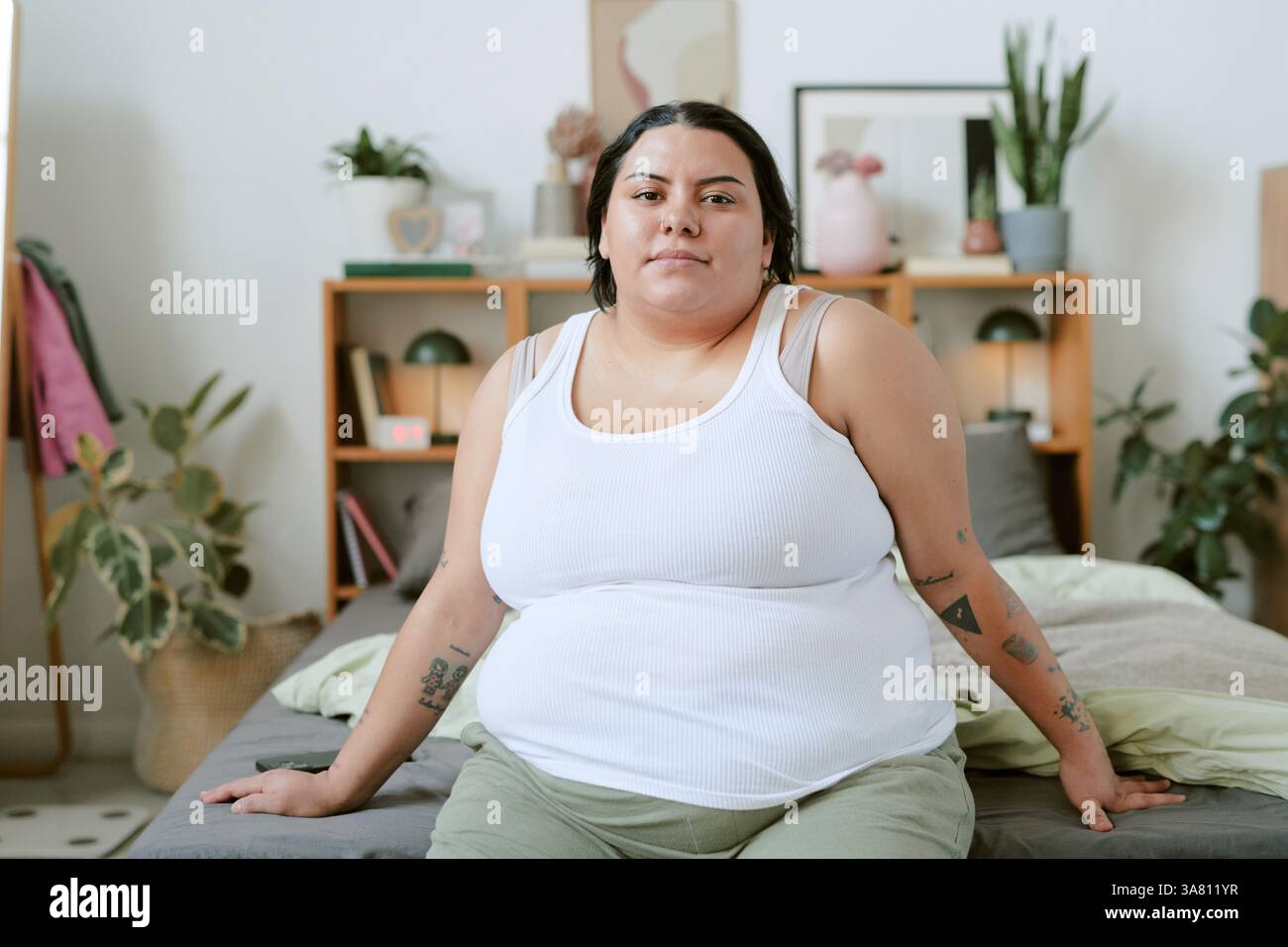 Porträt einer Frau, die auf dem Bett im friedlichen Raum sitzt Stockfoto