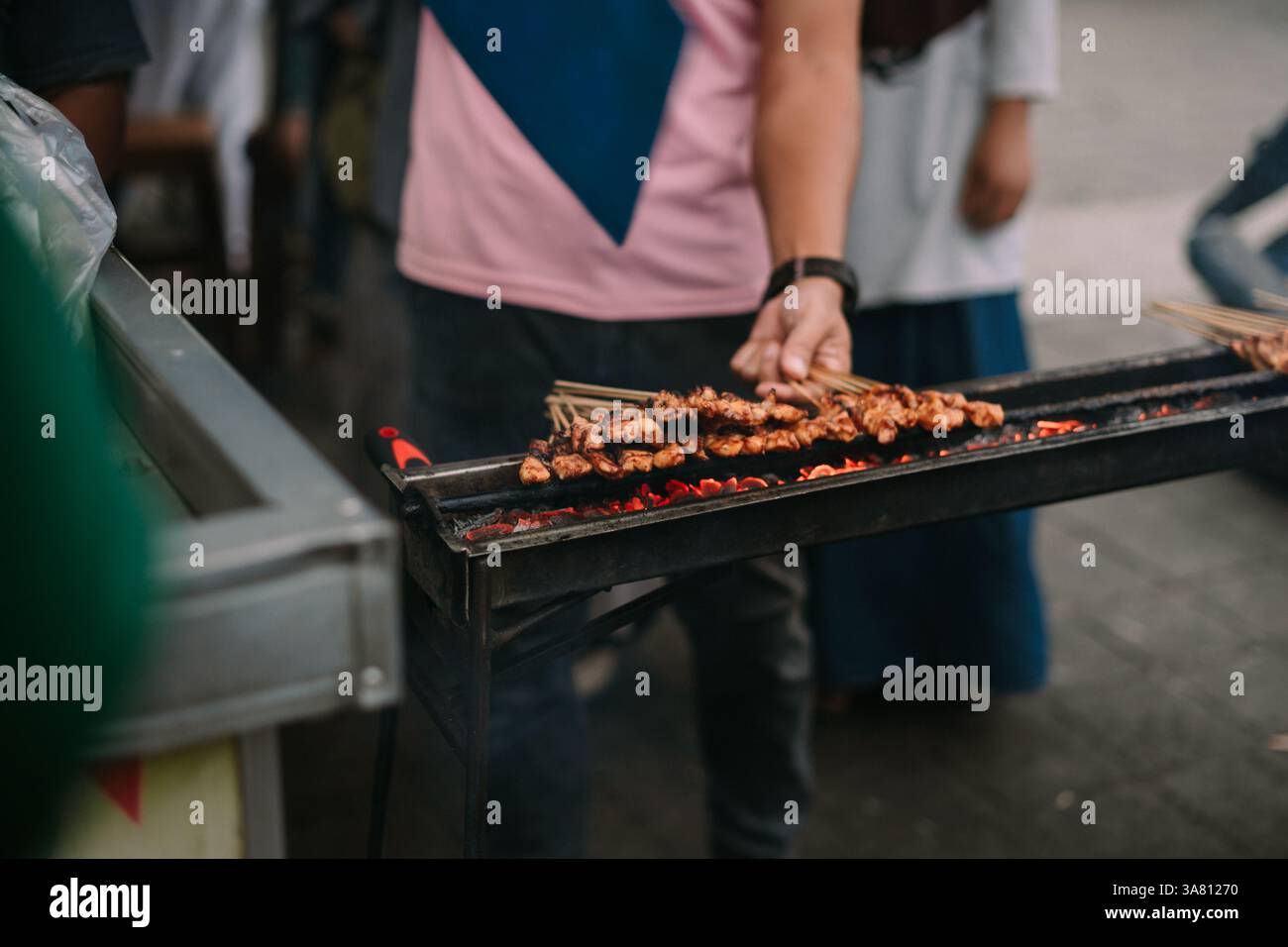 Nahaufnahme des Satay-Grills über heißer Holzkohle an einem Street Food-Stand. Diese geschmackvollen Hühnerspieße sind eine beliebte südostasiatische Delikatesse. Straße Stockfoto
