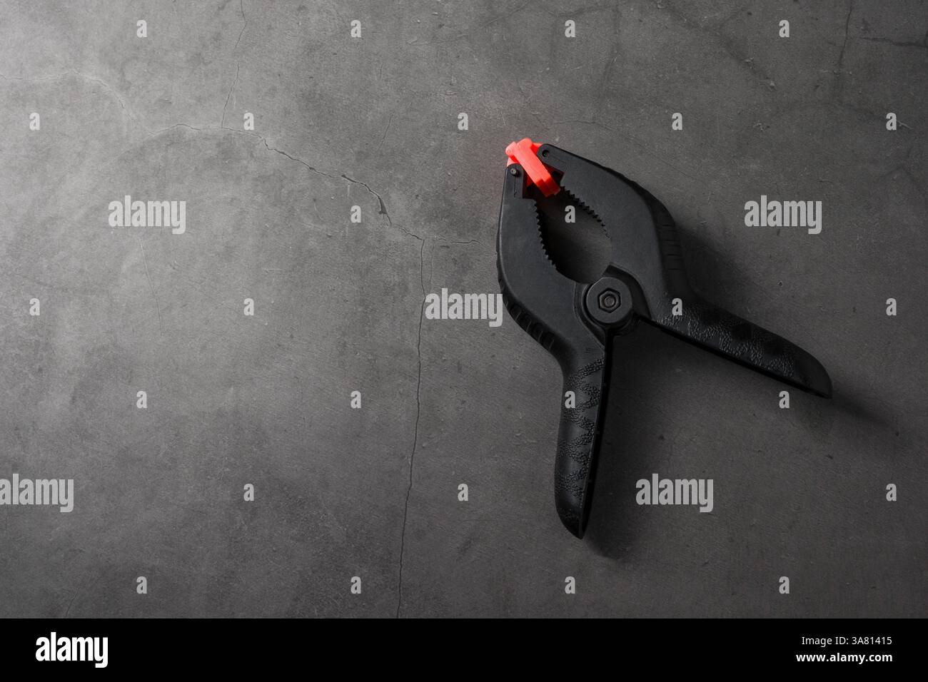 Orangefarbene schwarze Kunststoffklemme auf dunkelgrauem Steinhintergrund Stockfoto