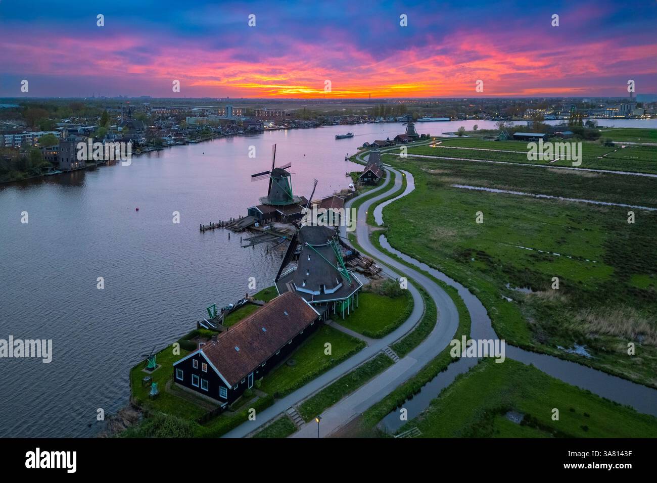 Luftaufnahme der typischen Windmühlen von Zaanse Schans auf dem Fluss Zaan im Frühling. Zaanse Schans, Nordholland, Gemeinde Zaanstad, Niederlande Stockfoto