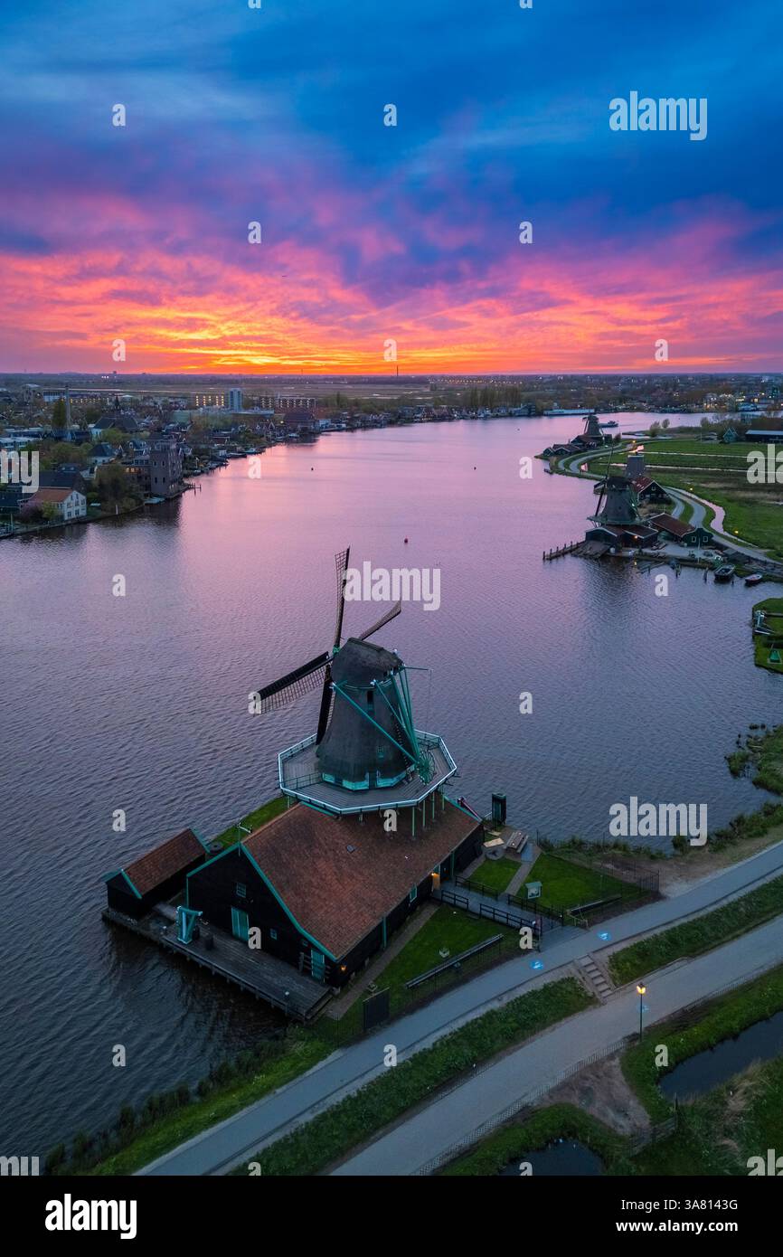 Luftaufnahme der typischen Windmühlen von Zaanse Schans auf dem Fluss Zaan im Frühling. Zaanse Schans, Nordholland, Gemeinde Zaanstad, Niederlande Stockfoto