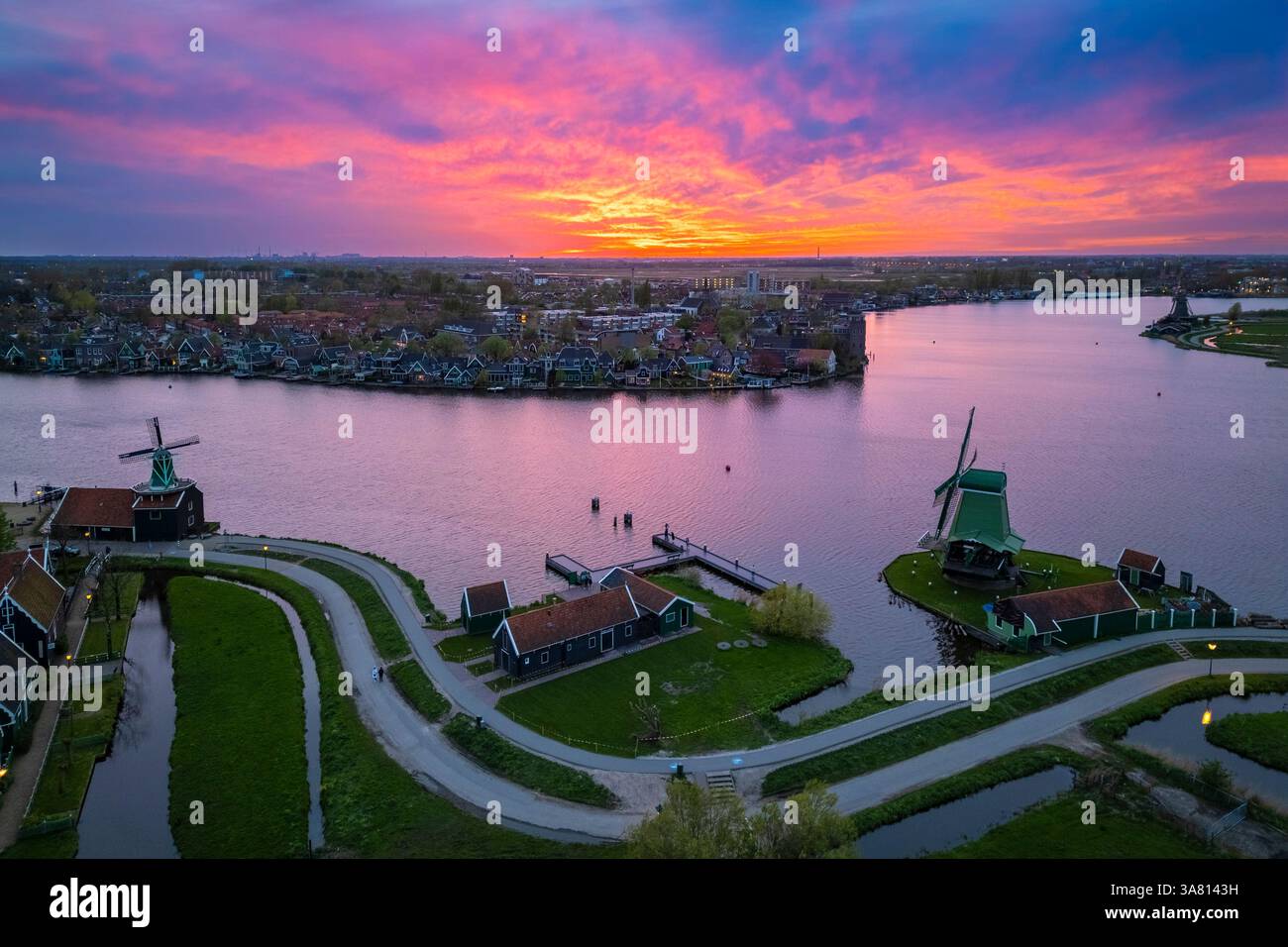 Luftaufnahme der typischen Windmühlen von Zaanse Schans auf dem Fluss Zaan im Frühling. Zaanse Schans, Nordholland, Gemeinde Zaanstad, Niederlande Stockfoto
