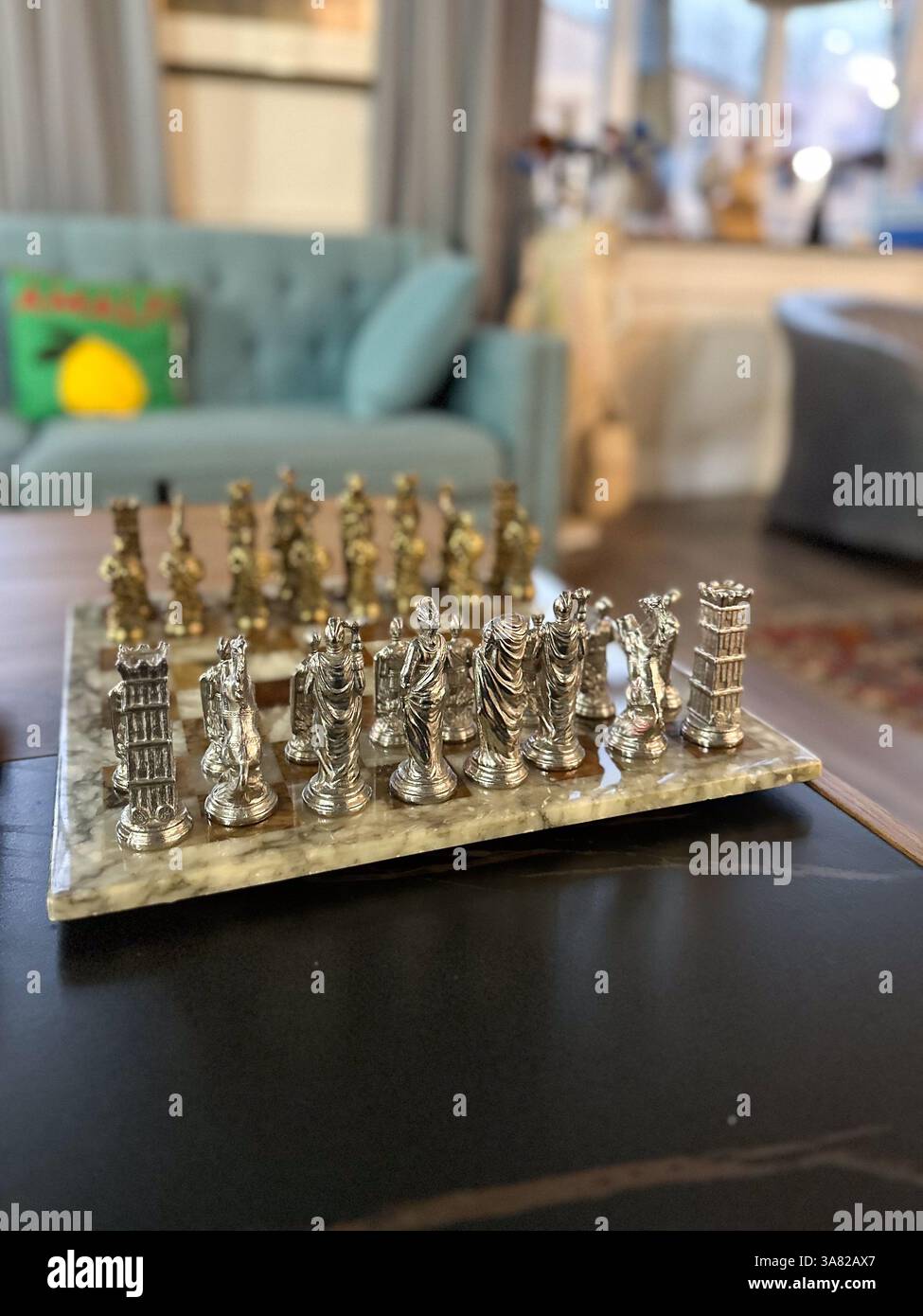 Elegantes Metallschach auf Marmorbrett im gemütlichen Wohnzimmer. Intelligenz, Strategie und zeitlose Freizeitgestaltung im Innenbereich. Stockfoto