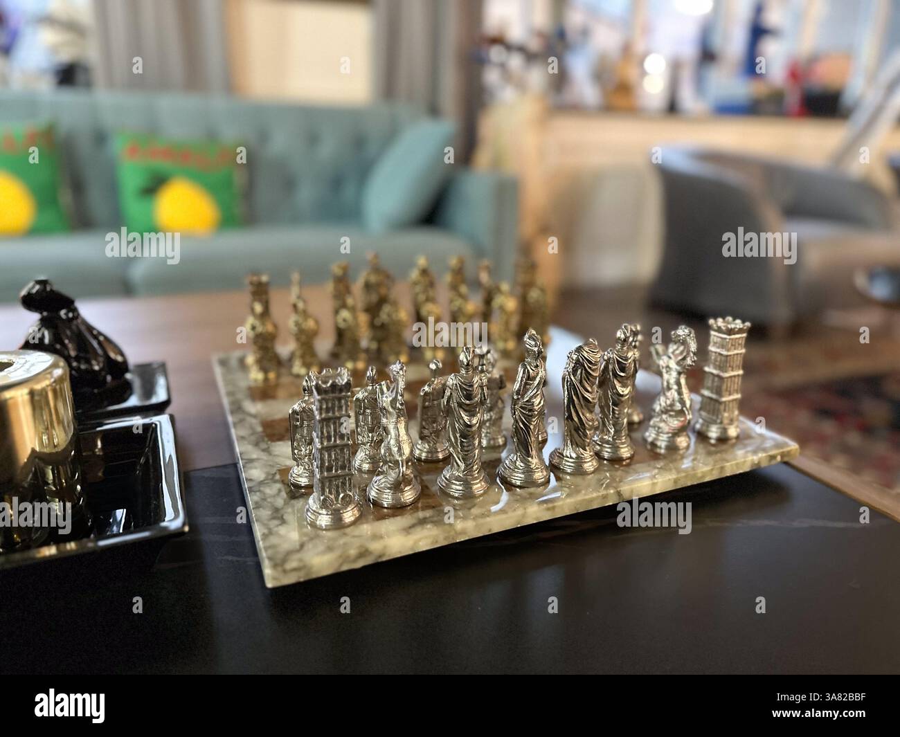 Elegantes Metallschach auf Marmorbrett im gemütlichen Wohnzimmer. Intelligenz, Strategie und zeitlose Freizeitgestaltung im Innenbereich. Stockfoto