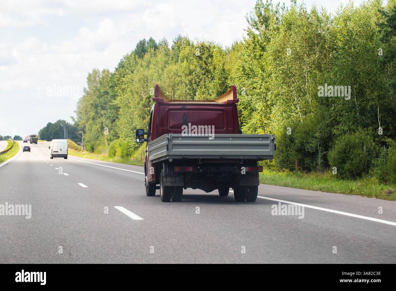 Ein offener Tieflader fährt im Sommer auf einer Autobahn. Transport von Gütern bis zu 5 Tonnen. Vermietung von Lkw für den regionalen und internationalen Transport Stockfoto