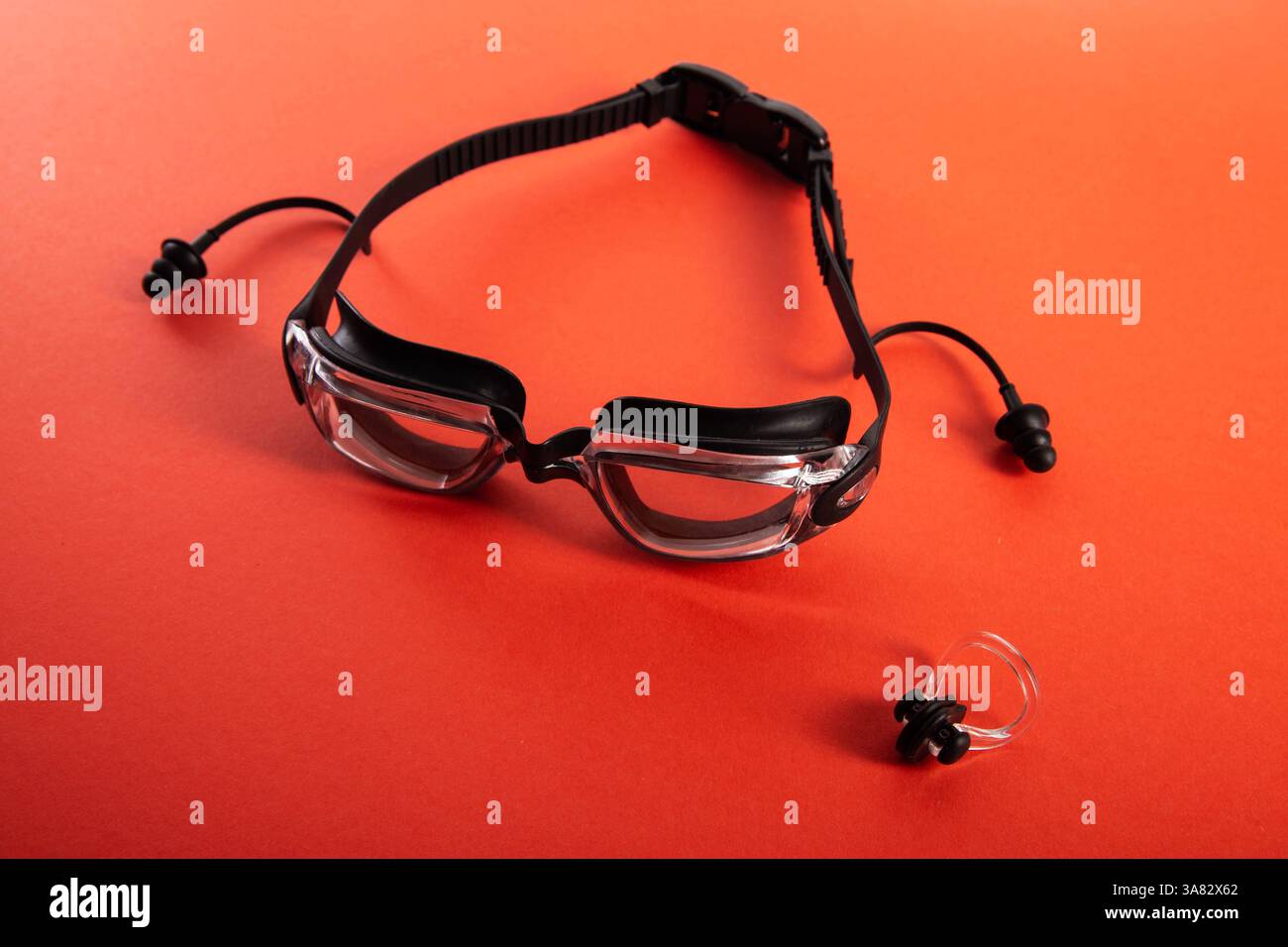 Schwimmbrille und Poolkappe mit Nasenclip auf rotem Hintergrund, isolieren Stockfoto