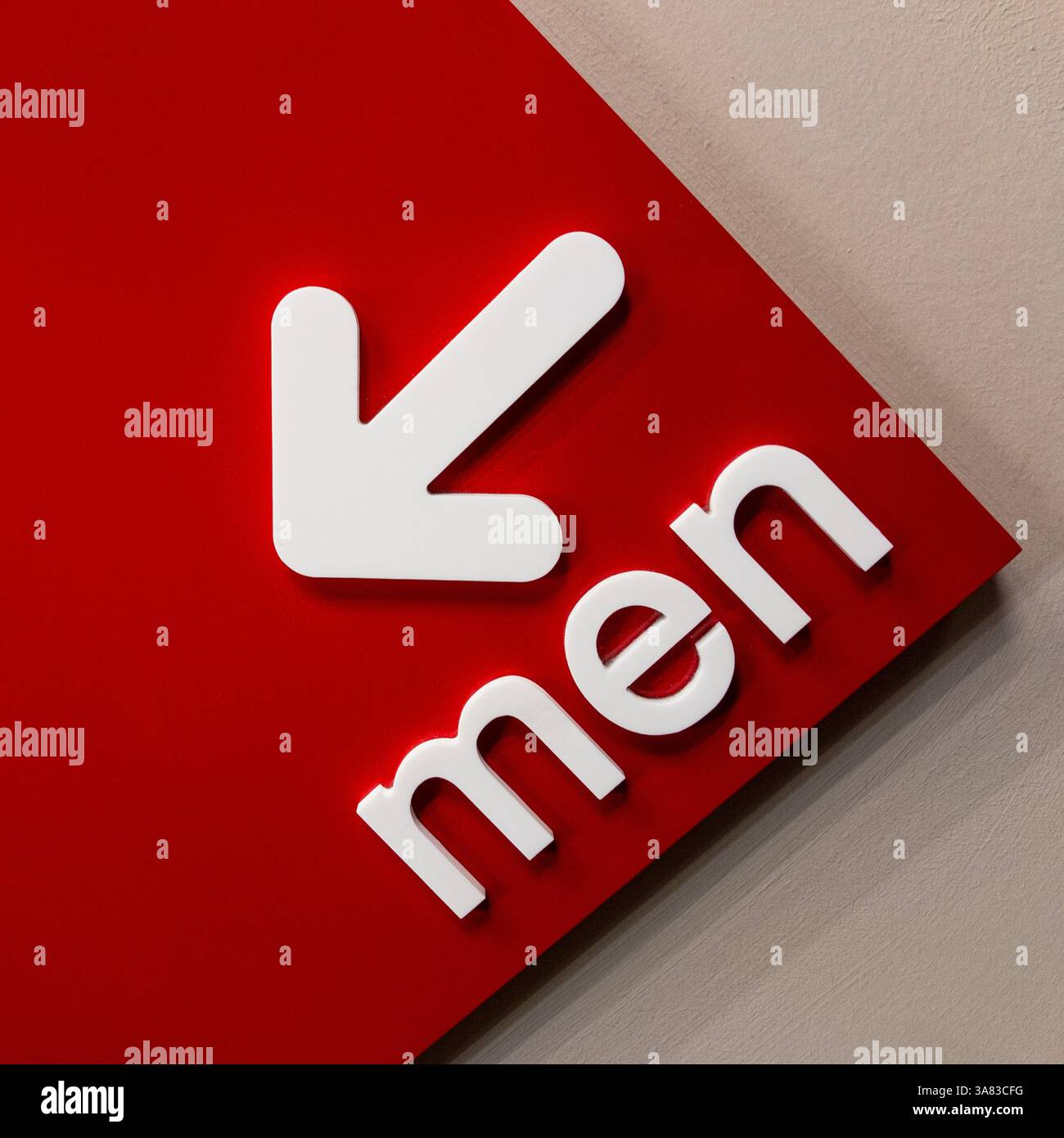 Rotes Wandschild mit dem Wort „men“ und einem Pfeil nach links. Stockfoto