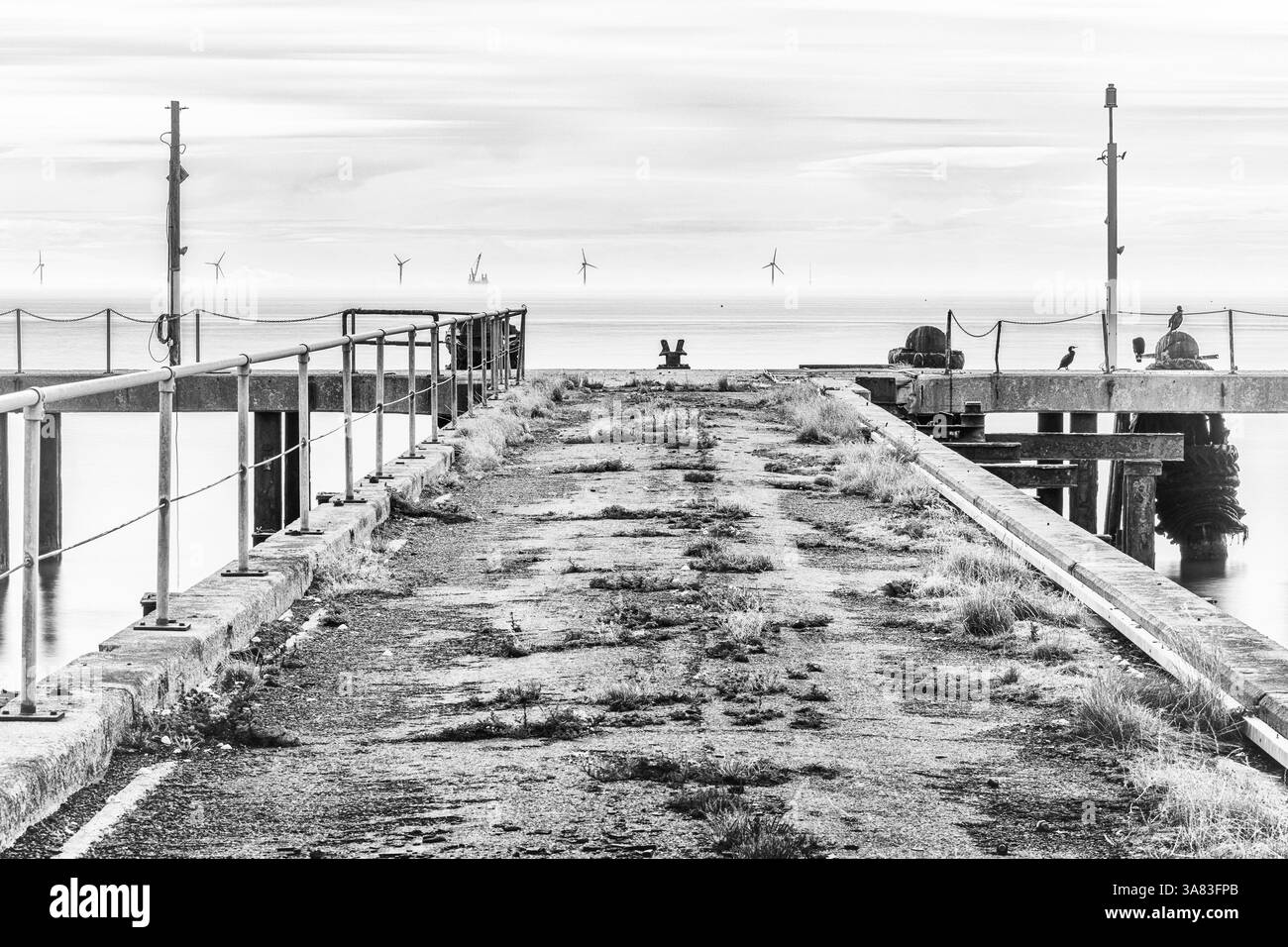 Alter Pier mit Seekraftanlagen in der Ferne Stockfoto