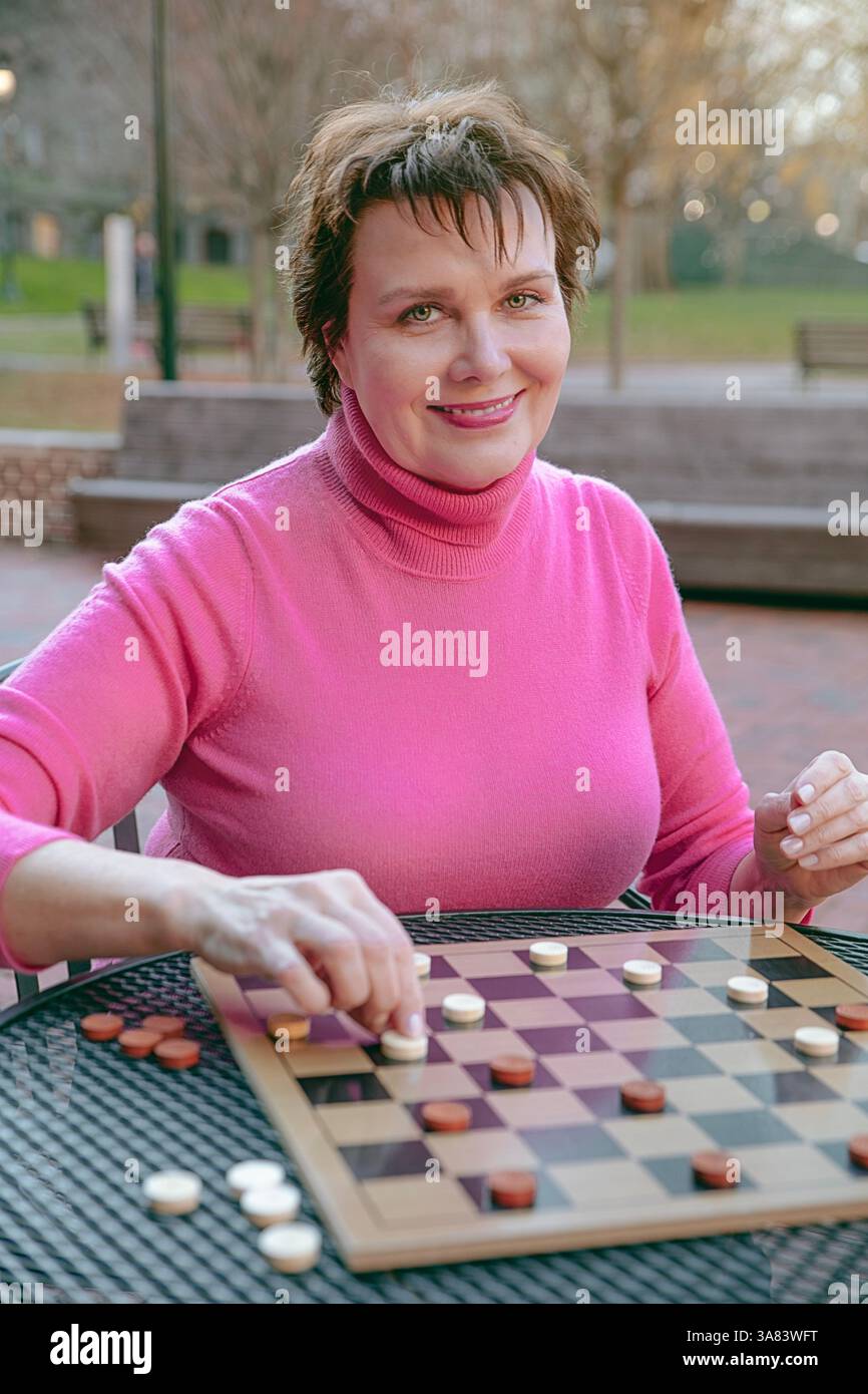 Die Frau bewegt sich mit ihrem Schachspieler und lächelt Stockfoto