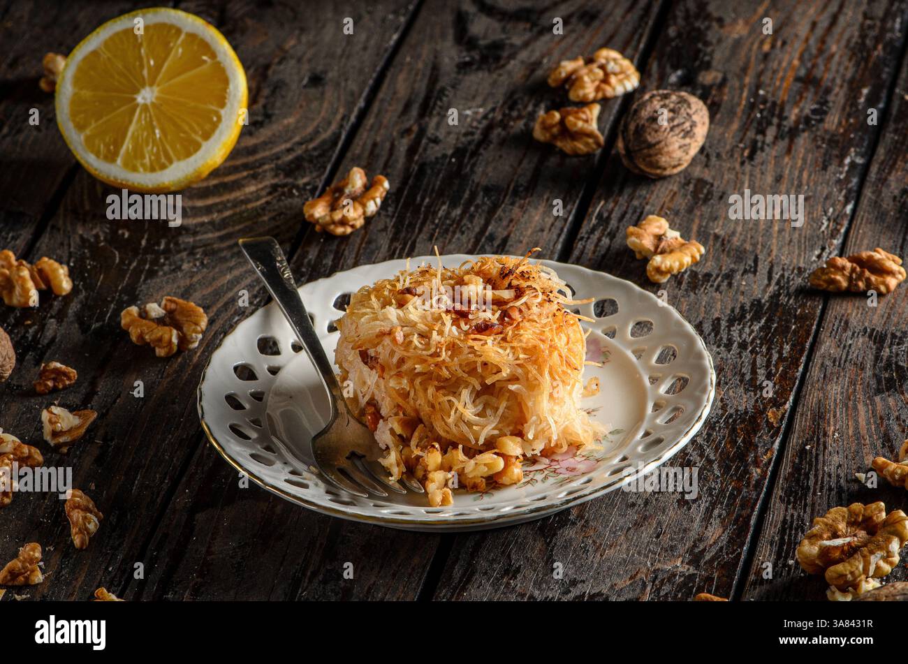Kadaif-Dessert, ein traditionelles süßes Gebäck aus dem Nahen Osten und dem Mittelmeerraum, serviert auf einer dunklen Holzoberfläche. Stockfoto