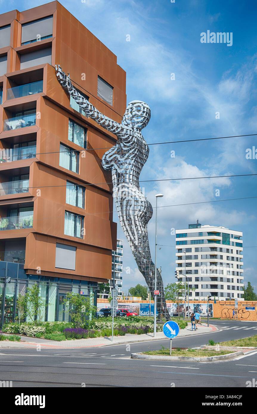 PRAG - 12. MAI 2024: Riesige Metallstatue, die nach einem zeitgenössischen Gebäude greift, von David Cherny in Prag, Tschechien, an einem sonnigen Sommertag Stockfoto PRAG - 12. MAI 2024: Riesige Metallstatue, die nach einem zeitgenössischen Gebäude greift, von David Cherny in Prag, Tschechien, an einem sonnigen Sommertag Stockfoto