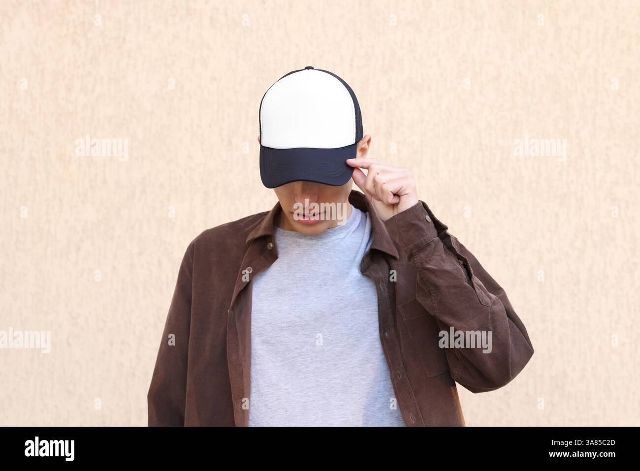 Mann in stilvoller Baseballmütze in der Nähe der beigefarbenen Wand. Modell für Design Stockfoto
