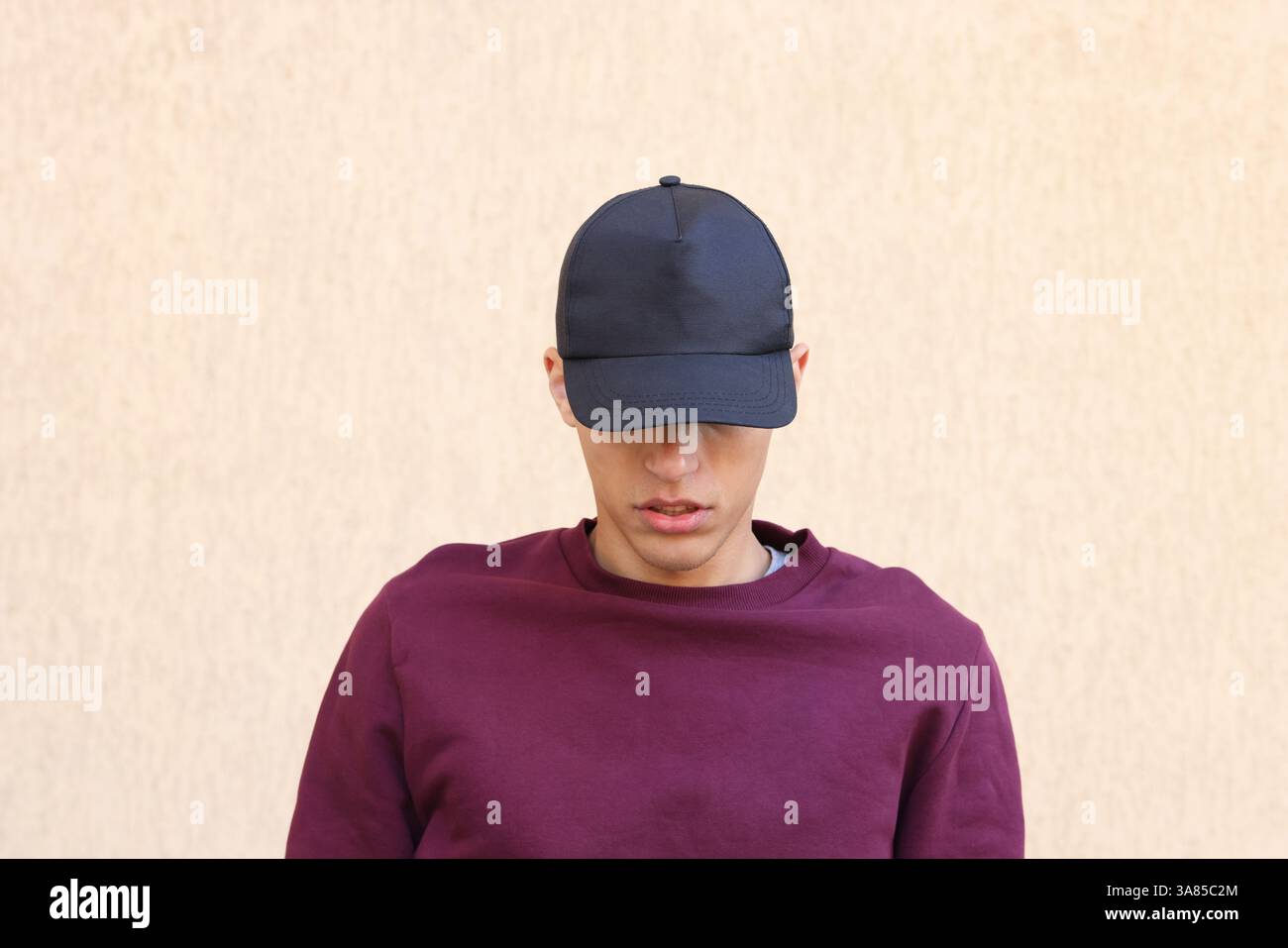 Mann in stilvoller Baseballmütze in der Nähe der beigefarbenen Wand. Modell für Design Stockfoto