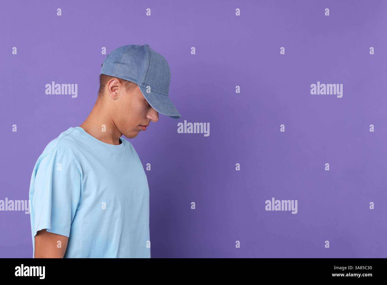 Mann in stilvoller Baseballmütze auf violettem Hintergrund. Modell für Design Stockfoto