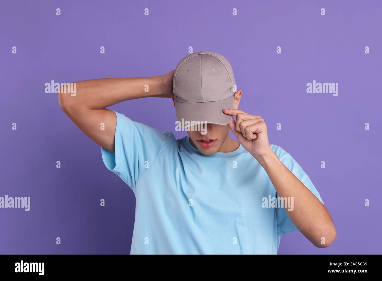 Mann in stilvoller Baseballmütze auf violettem Hintergrund. Modell für Design Stockfoto