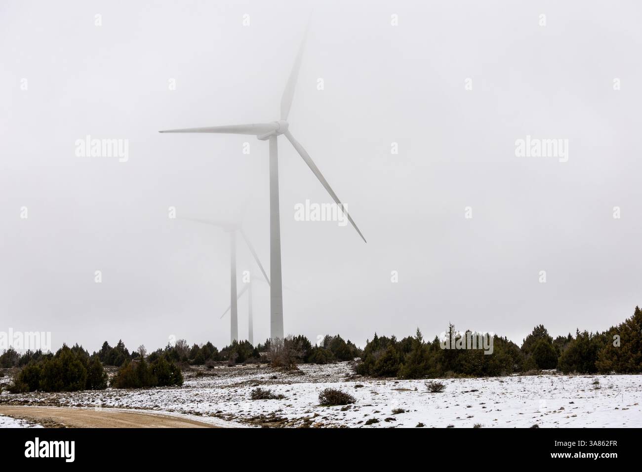 Windkraftanlage mit Schnee und Nebel Stockfoto