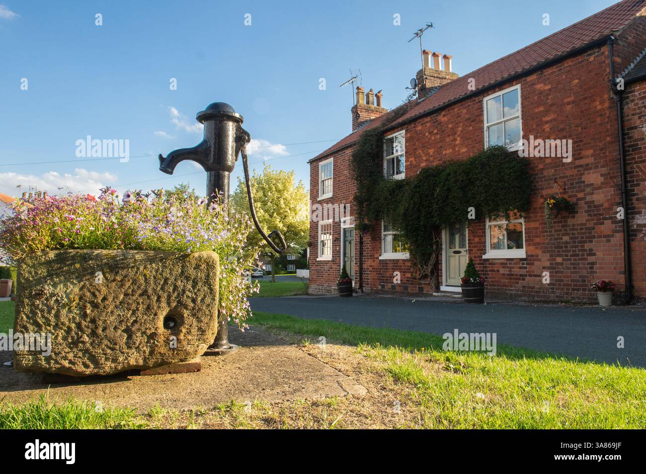 Eine alte Wasserpumpe vor einem Haus im Dorf Lund, einem Dorf und einer Gemeinde im East Riding of Yorkshire, England. Stockfoto