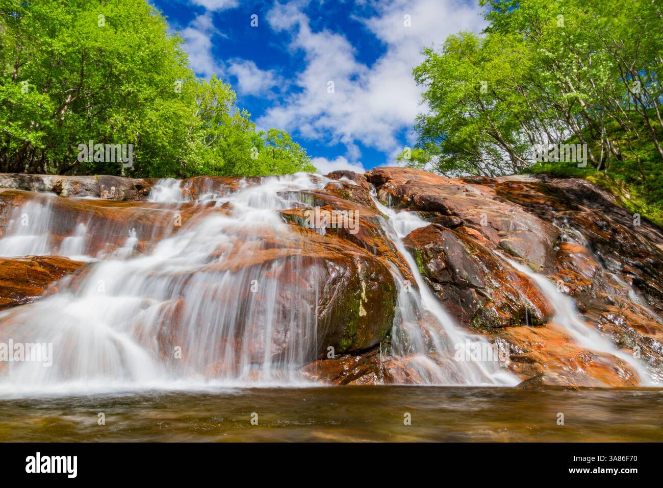 Ein wunderschöner Wasserfall außerhalb des kleinen norwegischen Sommergebietes in der Sandvika Bay auf der Südseite von Svesfjord, Norwegen Stockfoto