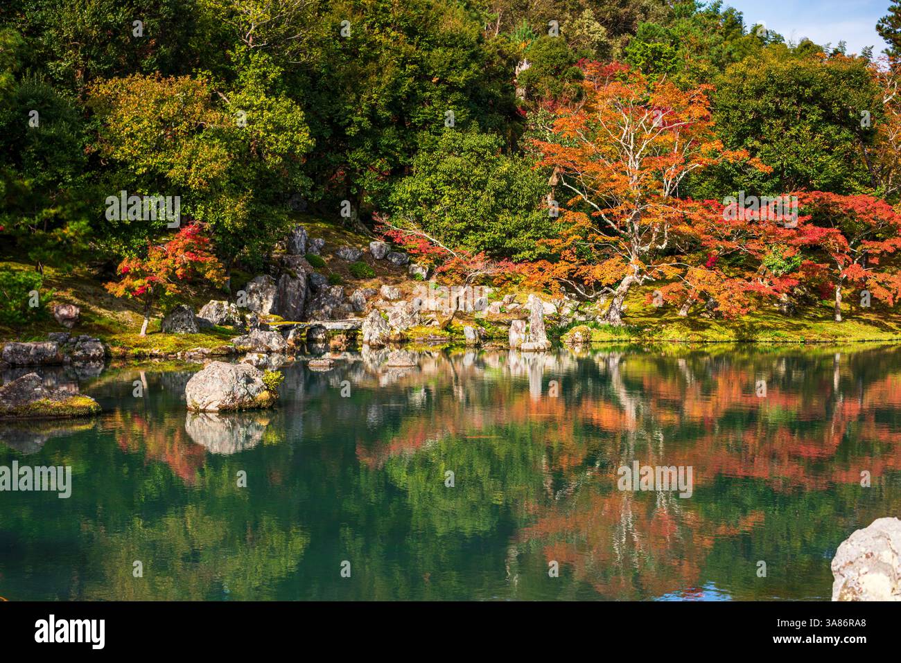 Herbstbäume spiegeln sich auf einem ruhigen Teich, umgeben von Felsen in den Gärten des Tenryu-JI Tempels, UNESCO, Kyoto, Honshu, Japan Stockfoto