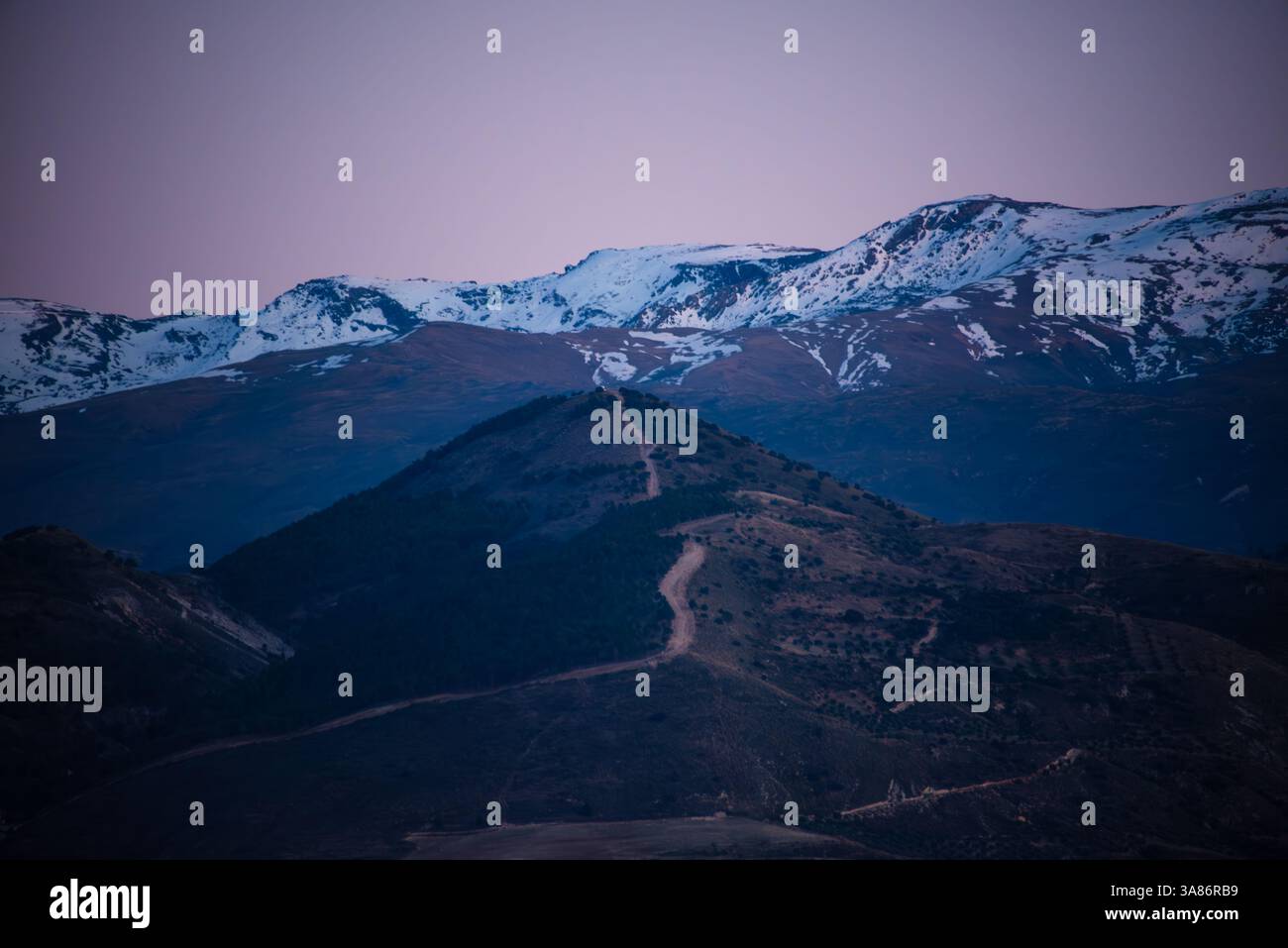 Violettes sanftes Licht am Abend über den schneebedeckten Gipfeln der Sierra Nevada, Andalusien, Spanien Stockfoto
