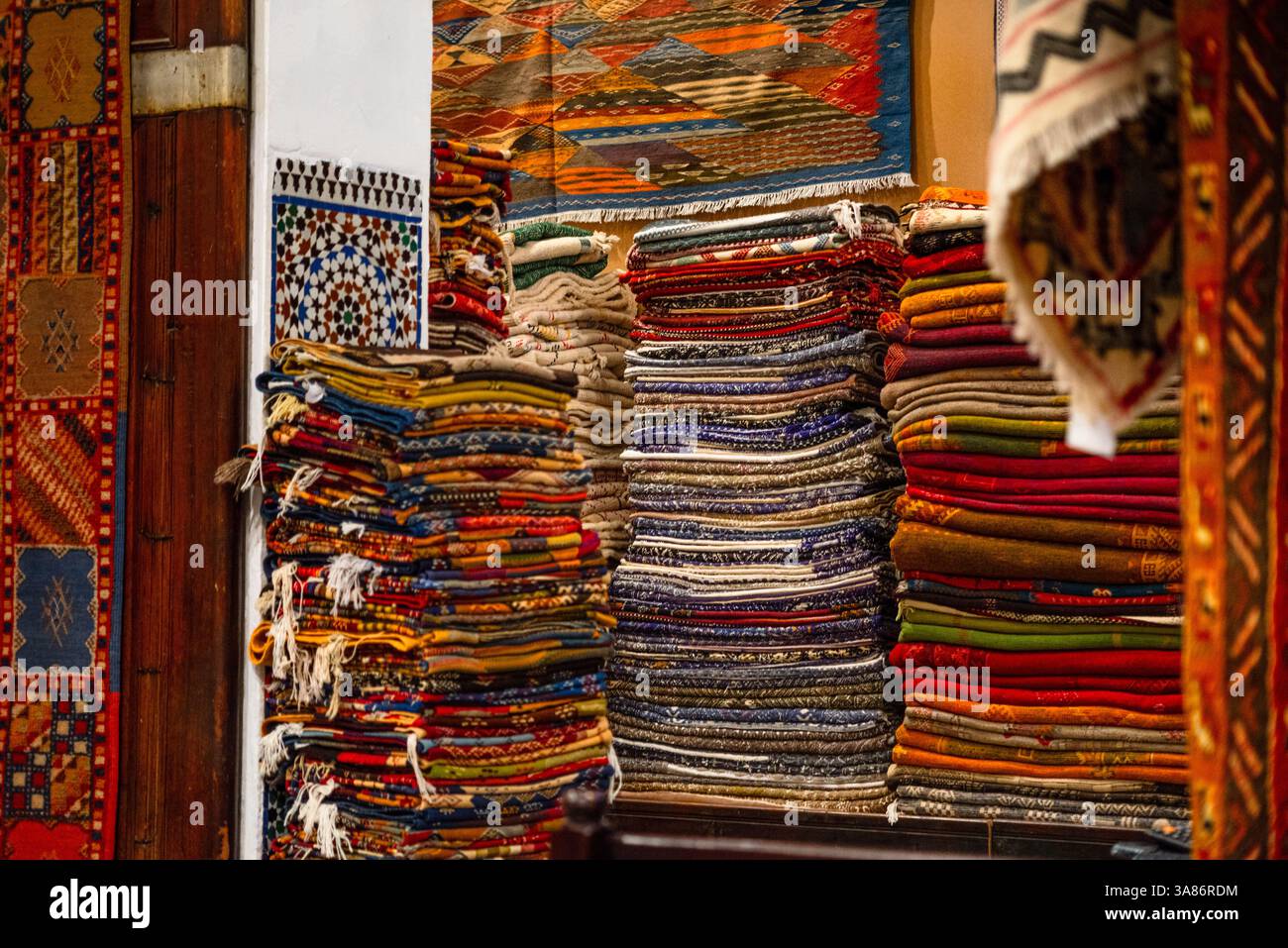 Stapel von lebhaften handgewebten marokkanischen Teppichen und Teppichen in einem traditionellen Geschäft in Fes, Marokko Stockfoto