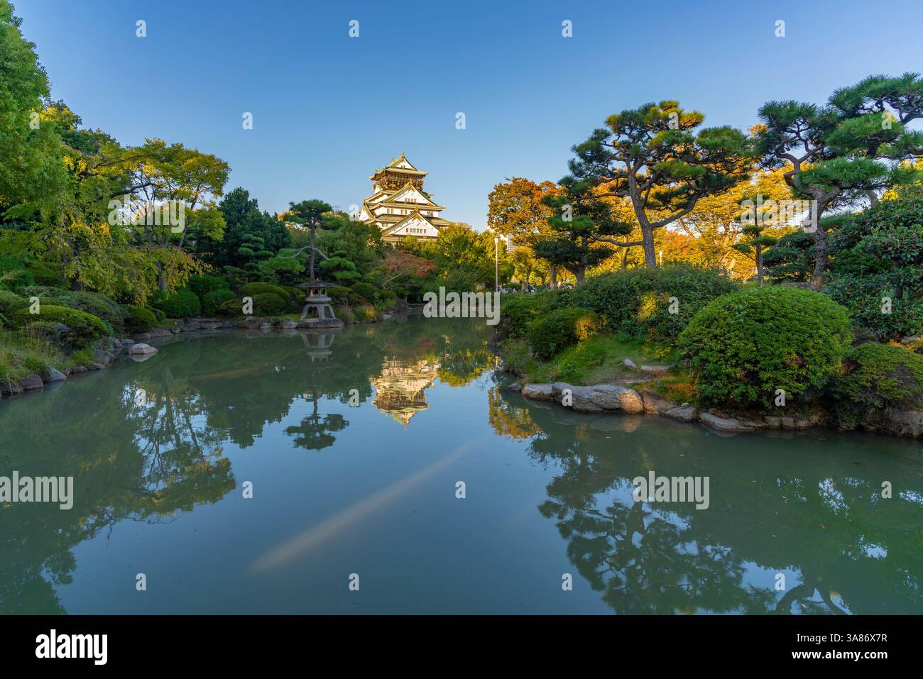 Blick auf das Schloss Osaka (Osaka-Jo), das sich bei Sonnenuntergang im japanischen Gartenteich spiegelt, Chuo Ward, Osaka, Honshu, Japan Stockfoto