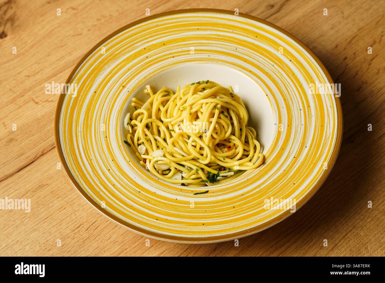 Eine wunderschön überzogene Portion Spaghetti Aaglio e olio, garniert mit frischer Petersilie und dünn geschnittenem Knoblauch. Die Pasta glitzert mit Olivenöl und h Stockfoto