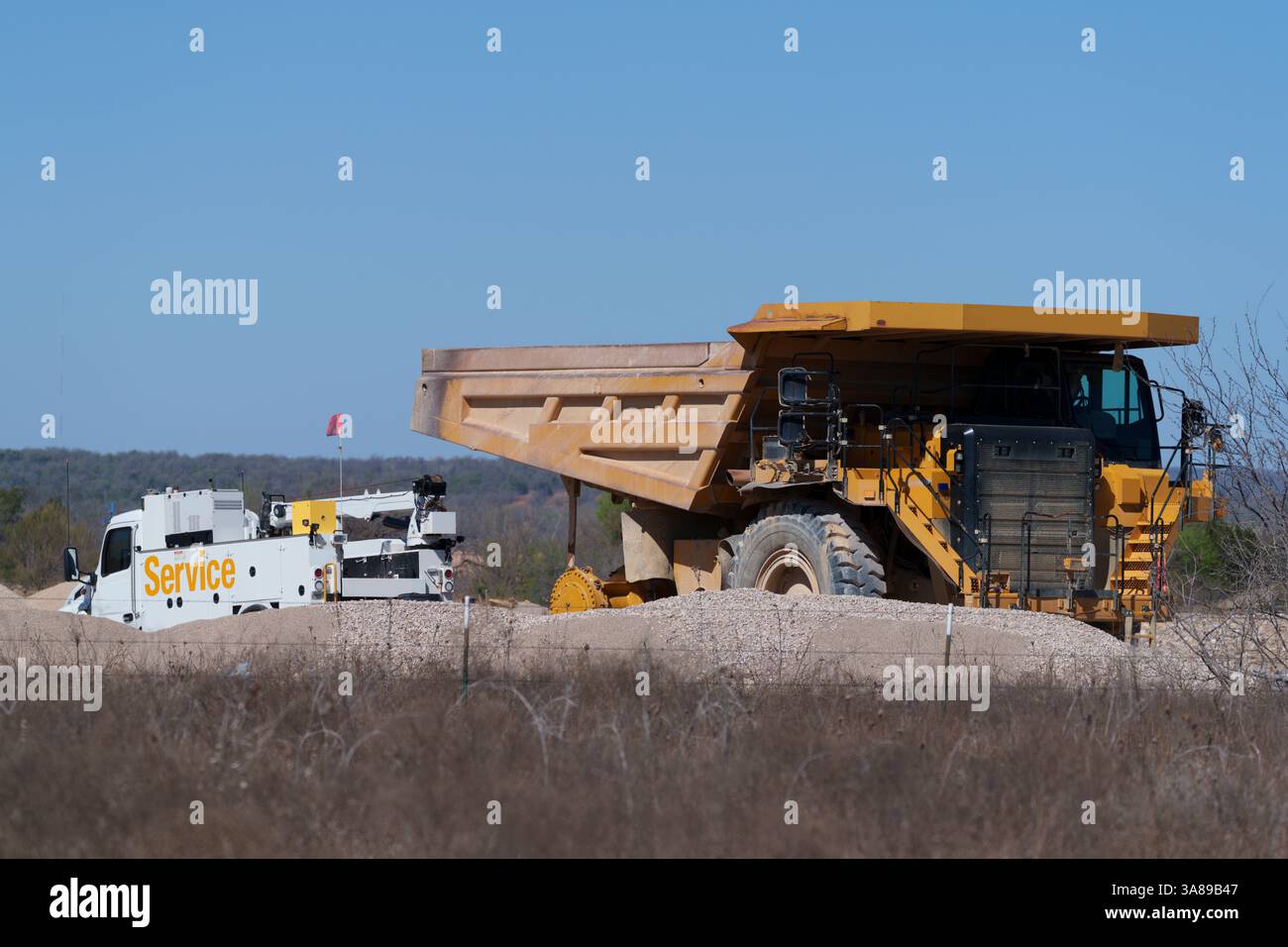 Ein sehr großer Muldenkipper wird in einem Steinbruch in West-Texas von einem mobilen Servicetrack vor Ort Reifenwechsel erhalten. Stockfoto