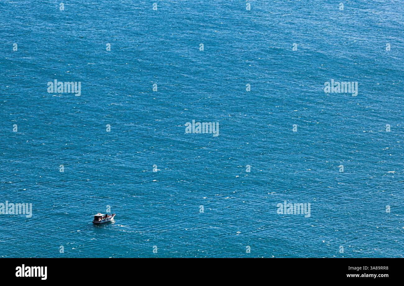 Einsames Boot in der weiten Weite des tiefblauen Meeres, aus der Luft. Perfekt für Reisethemen, Tranquility-Konzepte oder maritimen Designs. Stockfoto